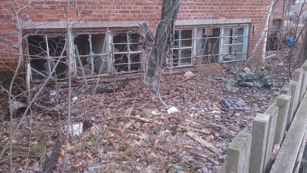 Ein leer stehendes Haus mit zerbrochenen Fenstern und zugemülltem Grundstück